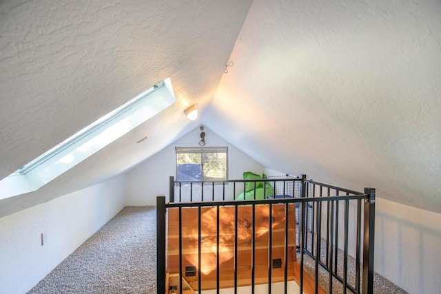 additional living space featuring a textured ceiling, vaulted ceiling with skylight, and carpet