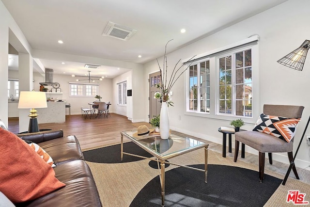 living room with plenty of natural light, wood-type flooring, and an inviting chandelier