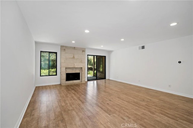 unfurnished living room with light wood-type flooring and a large fireplace