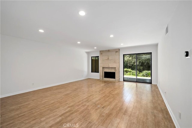 unfurnished living room with a large fireplace and light hardwood / wood-style flooring