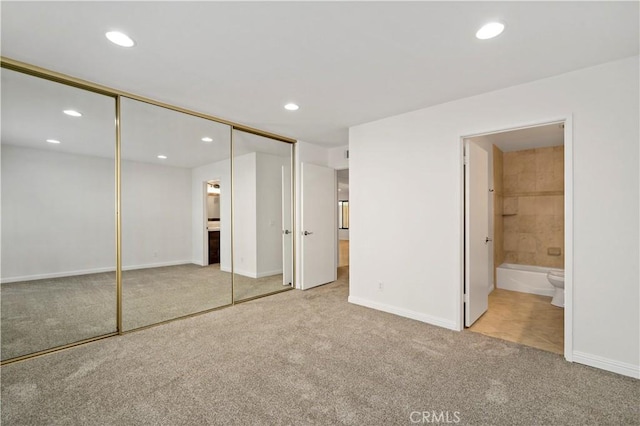 unfurnished bedroom with light colored carpet, connected bathroom, and a closet