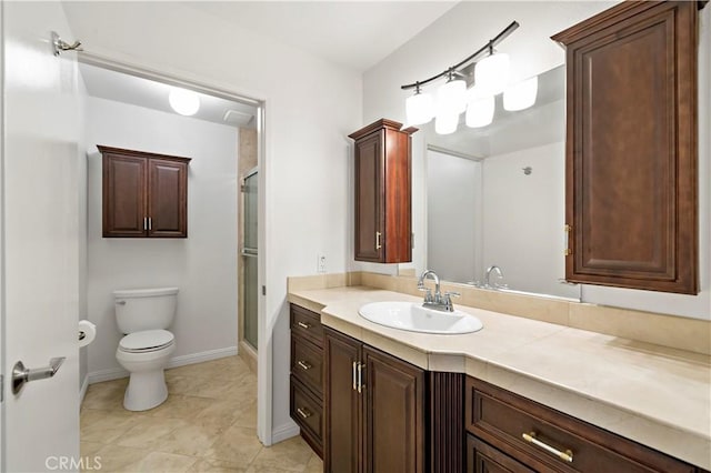 bathroom featuring tile patterned flooring, vanity, toilet, and a shower with door