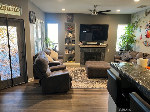 living room with ceiling fan, hardwood / wood-style flooring, and a tile fireplace