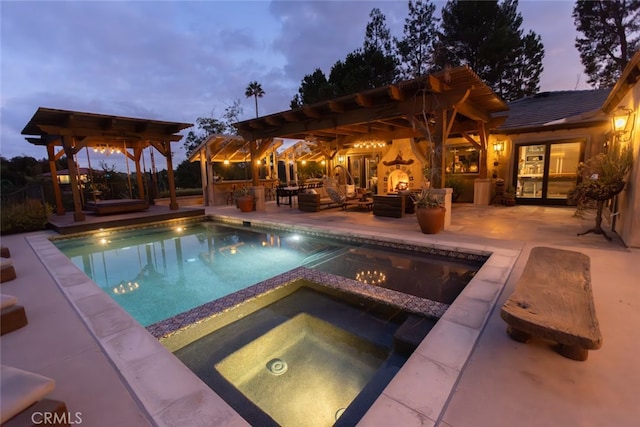 pool at dusk with an in ground hot tub and a patio