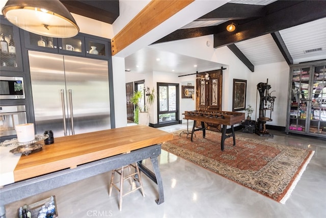 interior space with vaulted ceiling with beams and a barn door