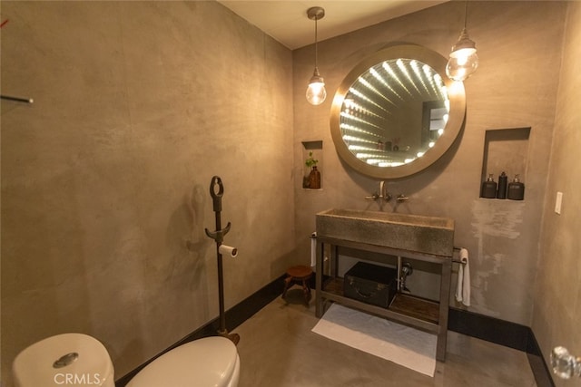 bathroom with toilet, concrete floors, and sink