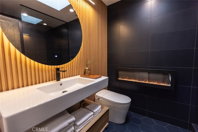 bathroom featuring toilet, sink, tile patterned floors, and tile walls