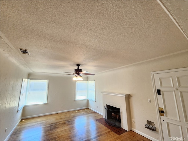 unfurnished living room featuring a brick fireplace, hardwood / wood-style flooring, a textured ceiling, and ceiling fan