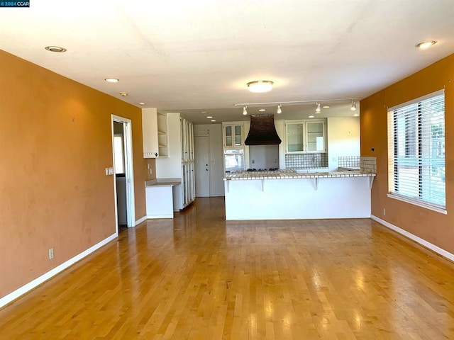 kitchen featuring white oven, tasteful backsplash, a kitchen breakfast bar, kitchen peninsula, and hardwood / wood-style floors