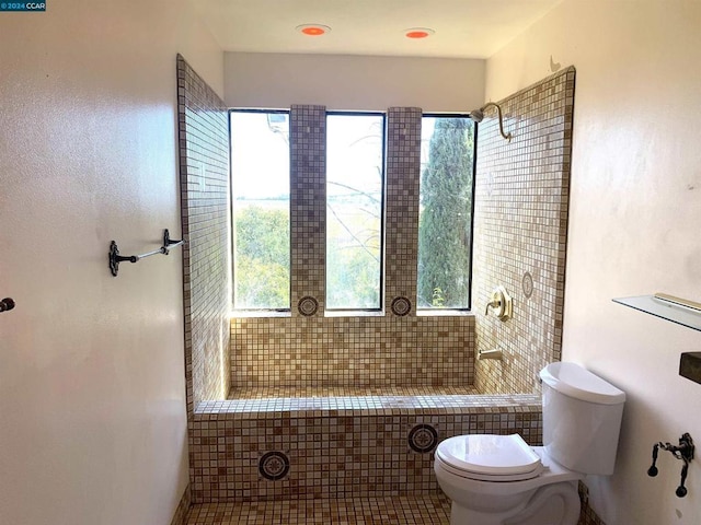 bathroom with a healthy amount of sunlight, toilet, and tiled shower