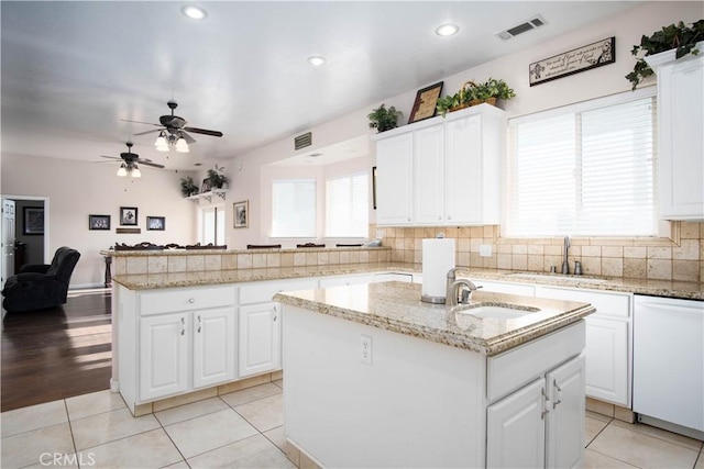 kitchen with dishwasher, light tile patterned floors, a center island with sink, and white cabinets