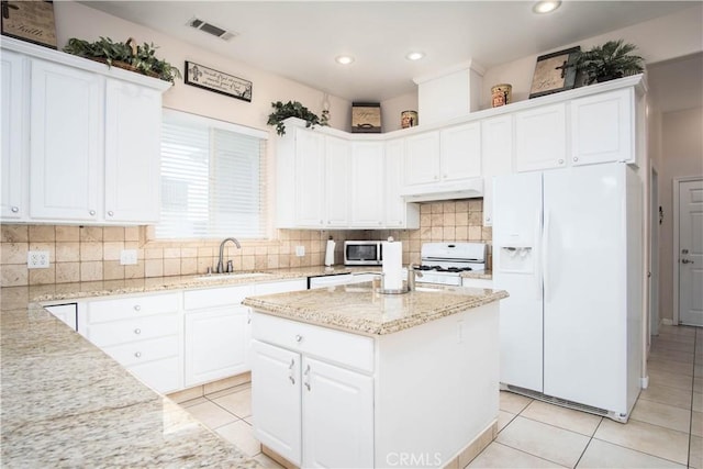 kitchen featuring light tile patterned flooring, sink, white cabinetry, light stone counters, and white appliances