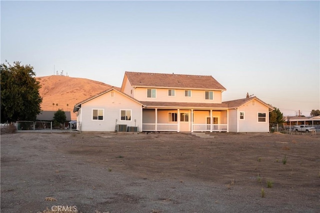 back house at dusk with cooling unit, a mountain view, and covered porch