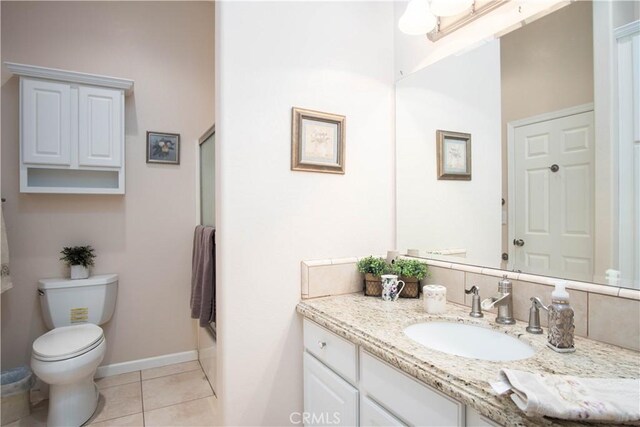 bathroom with a shower with door, vanity, tile patterned floors, and toilet