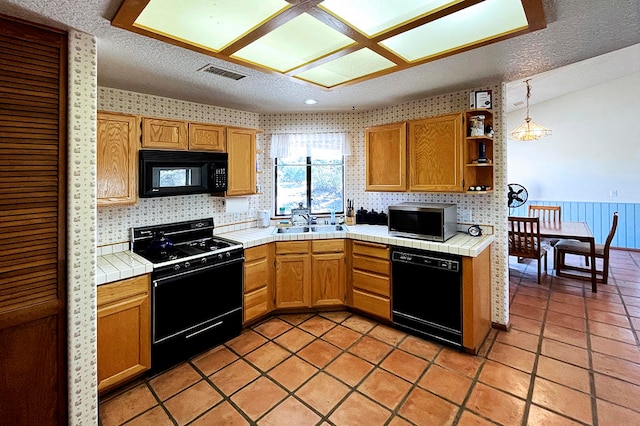 kitchen featuring pendant lighting, tile countertops, sink, and black appliances