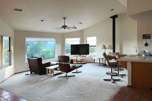 living room with a textured ceiling, vaulted ceiling, light carpet, and ceiling fan