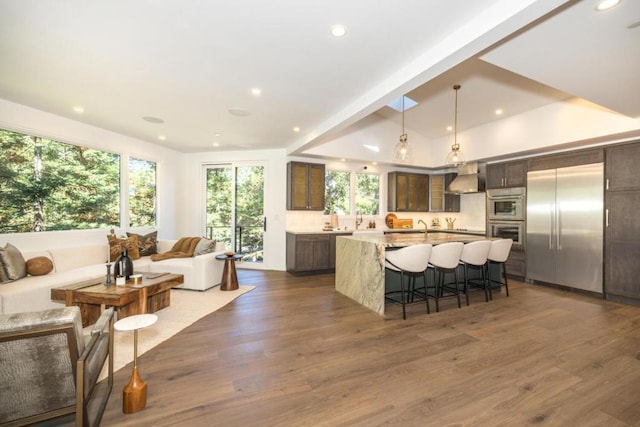 kitchen featuring hanging light fixtures, dark wood-type flooring, extractor fan, appliances with stainless steel finishes, and a spacious island