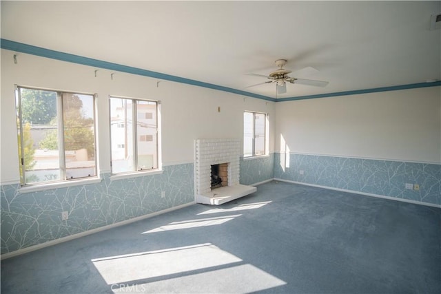 unfurnished living room with ceiling fan, ornamental molding, plenty of natural light, and a brick fireplace