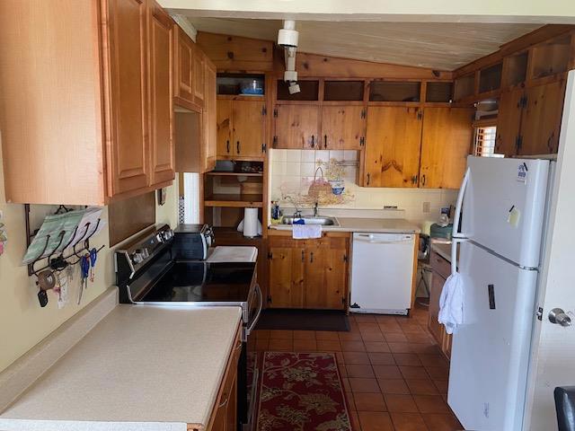 kitchen featuring sink, dark tile patterned flooring, and white appliances