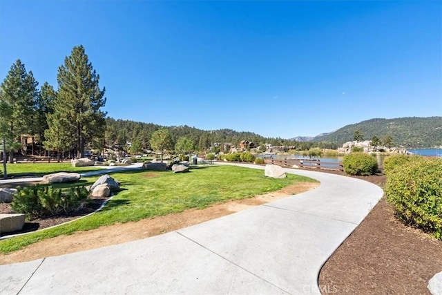 view of home's community featuring a water and mountain view and a yard