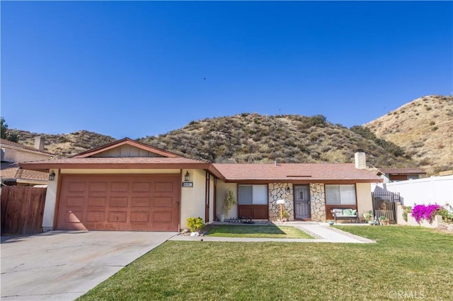 single story home featuring concrete driveway, fence, a mountain view, a garage, and a front lawn