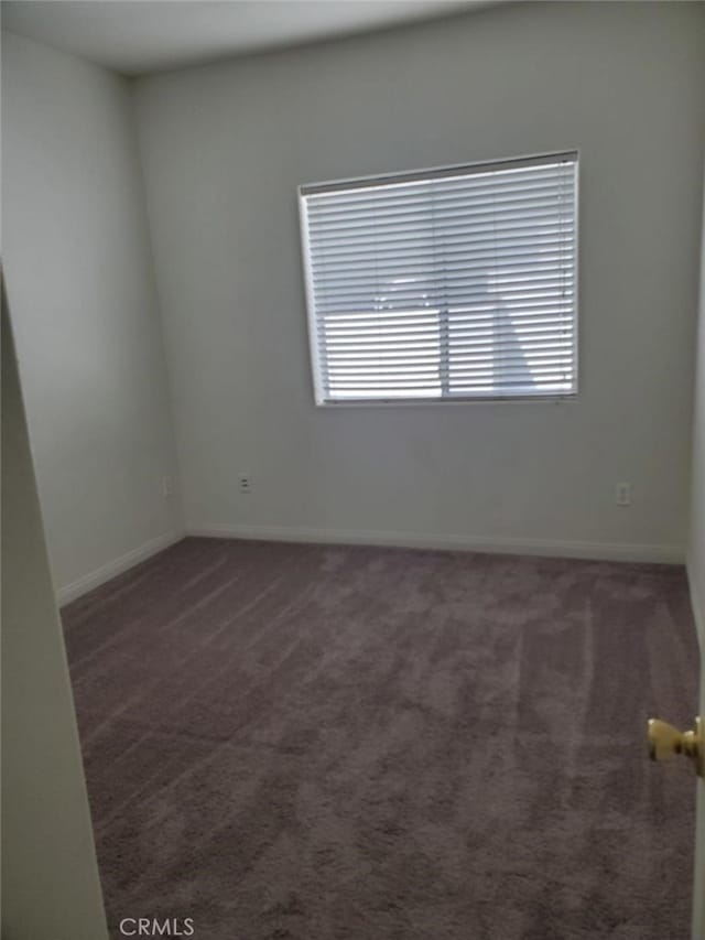 unfurnished room featuring dark colored carpet and plenty of natural light