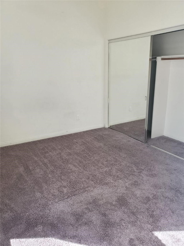 unfurnished bedroom featuring dark carpet and a closet