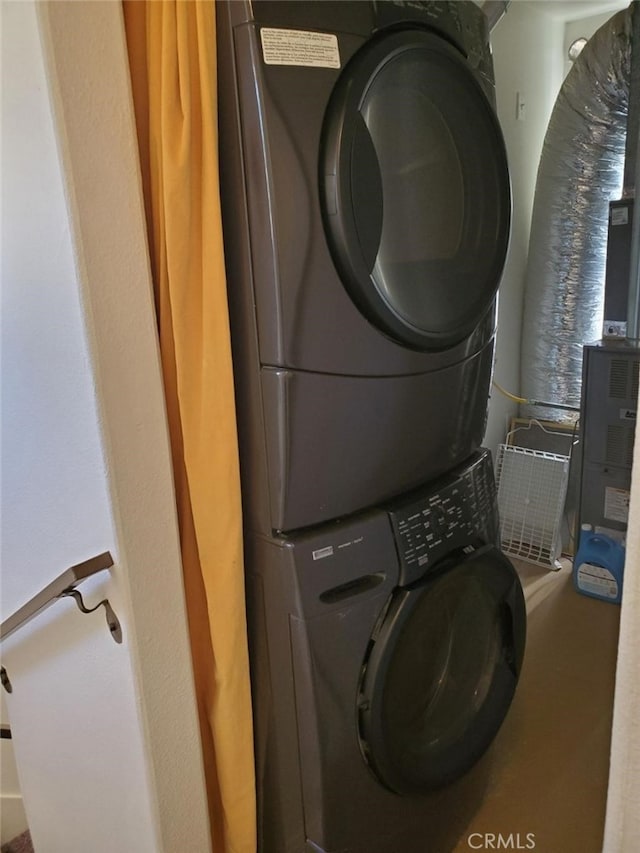 clothes washing area featuring stacked washing maching and dryer