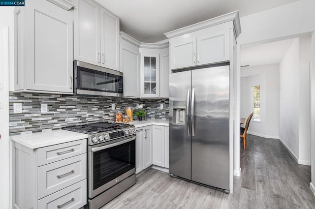 kitchen with decorative backsplash, light wood-type flooring, white cabinetry, and stainless steel appliances