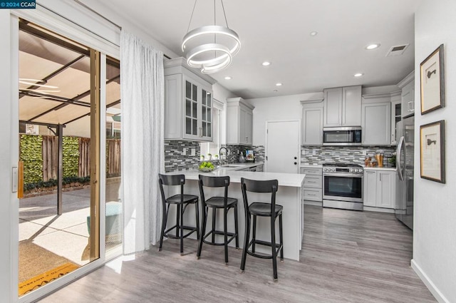 kitchen featuring tasteful backsplash, kitchen peninsula, a breakfast bar, and stainless steel appliances