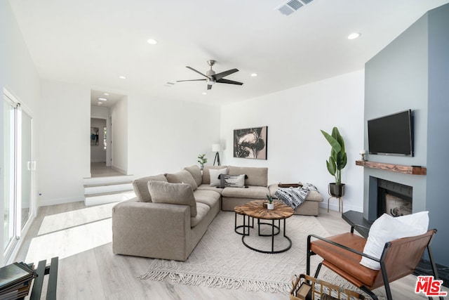 living room featuring ceiling fan, light wood-type flooring, and a wealth of natural light