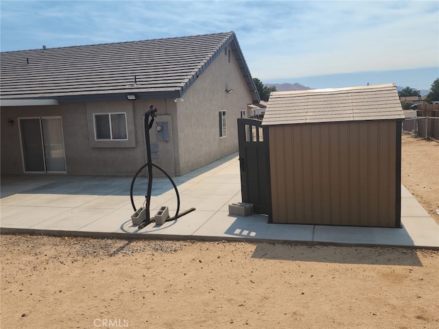 rear view of house with a storage shed and a patio