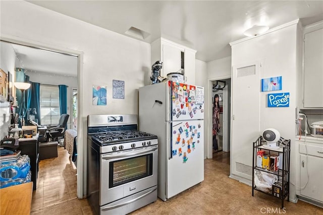 kitchen featuring white cabinetry, stainless steel gas stove, and white fridge