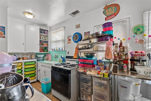 kitchen with white cabinets, light tile patterned floors, sink, and white range with gas cooktop