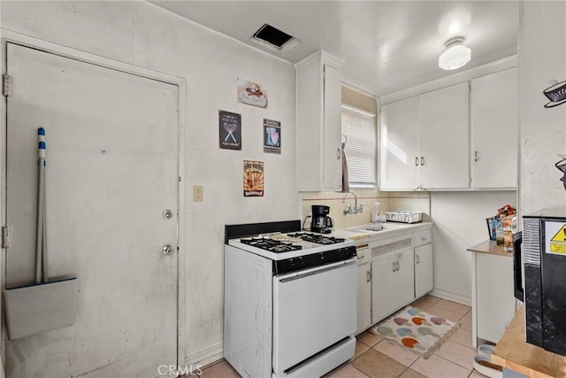 kitchen featuring white cabinets, light tile patterned flooring, sink, and white range with gas cooktop