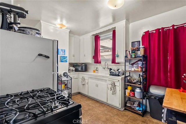 kitchen featuring backsplash, white cabinetry, sink, and black appliances