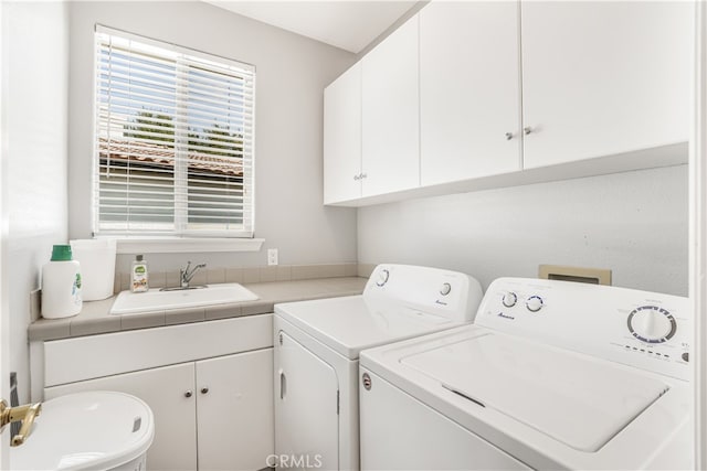 washroom with separate washer and dryer, cabinets, and sink