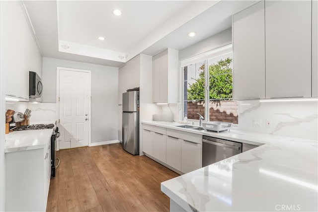 kitchen featuring light stone counters, appliances with stainless steel finishes, light wood-type flooring, and decorative backsplash