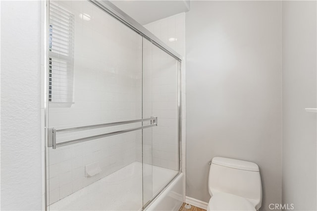 bathroom featuring enclosed tub / shower combo and toilet