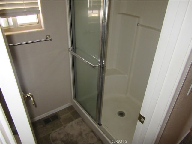 bathroom with a shower with door and tile patterned floors