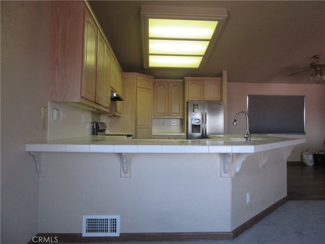 kitchen with a kitchen bar, stainless steel appliances, tile counters, and kitchen peninsula