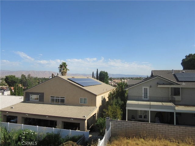 view of side of home with a balcony, solar panels, and a mountain view