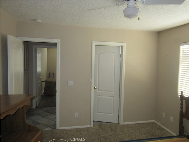 carpeted bedroom with ceiling fan and a textured ceiling