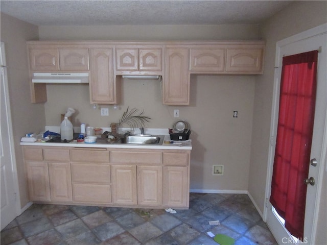 kitchen featuring light brown cabinets, a textured ceiling, and sink