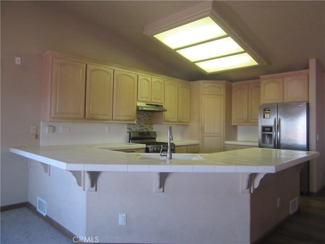 kitchen featuring a breakfast bar, appliances with stainless steel finishes, kitchen peninsula, and tile counters