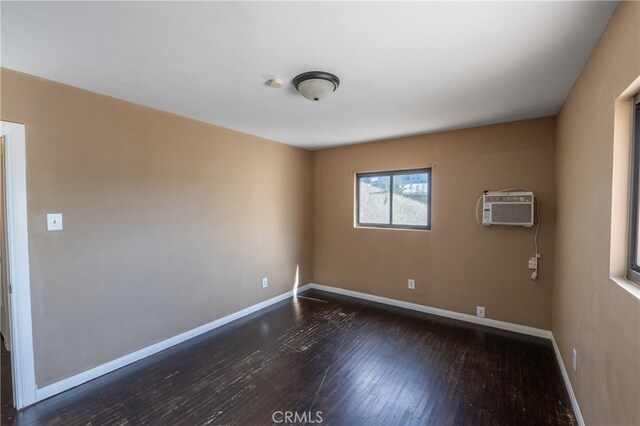 unfurnished room featuring a wall mounted air conditioner and dark hardwood / wood-style floors