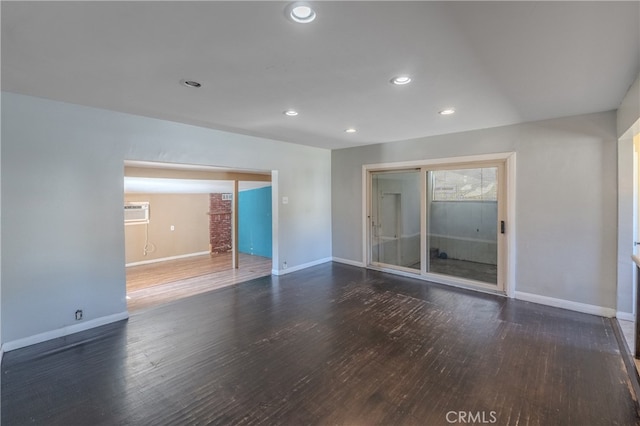 spare room with a wall unit AC and dark hardwood / wood-style flooring