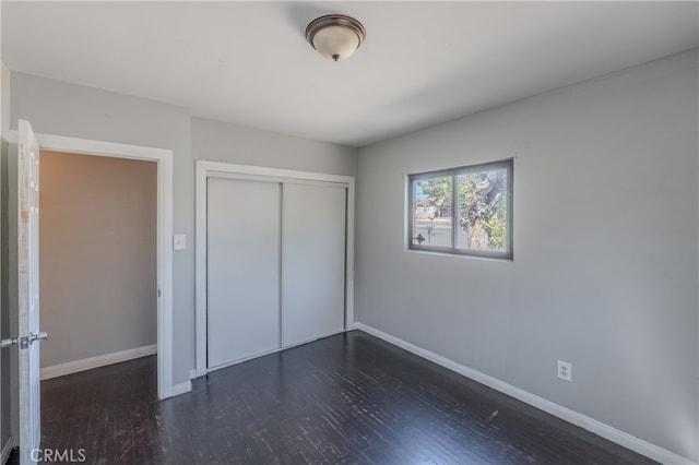 unfurnished bedroom featuring a closet and dark hardwood / wood-style floors