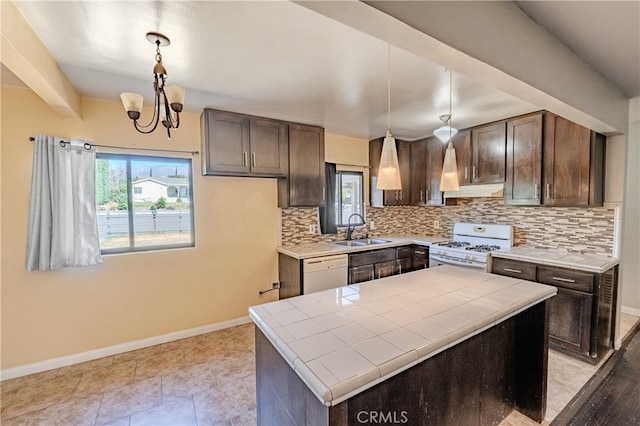 kitchen with sink, white appliances, pendant lighting, and tile counters