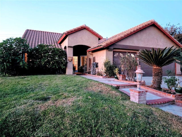 mediterranean / spanish-style home featuring a garage and a front yard